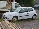 a small white car that is parked in front of a truck