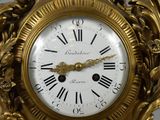 a gold clock with roman numerals on the face