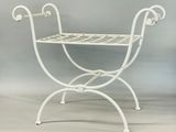 a white iron bench with a basket on it