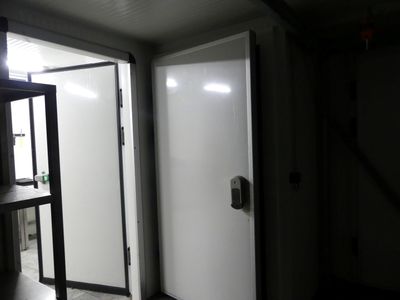une porte blanche dans une pièce sombre, à côté d'une étagère