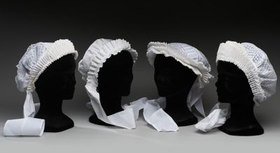trois têtes de mannequins noires ornées de volants blancs et un rouleau de papier toilette
