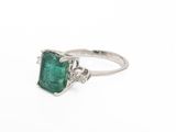 an emerald and diamond ring on a white background