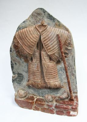 statue d'un homme tenant un bâton, posée sur un bloc de pierre