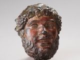 sculpture représentant la tête d'un homme barbu aux cheveux bouclés