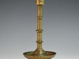 an antique brass candle holder on a white surface