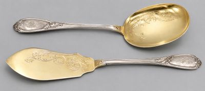 pair of silver spoons with engraved designs on them on a gray surface