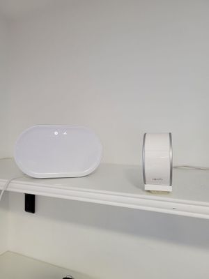 un haut-parleur blanc posé sur une étagère à côté d'une souris