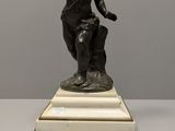 statue en bronze représentant un garçon, posée sur un socle en marbre