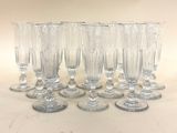 six verres à vin transparents sont alignés sur une surface blanche
