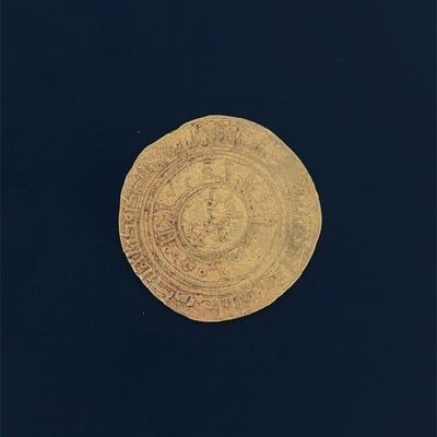 an old gold coin on a black surface with a black background