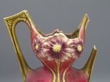 un vase rose et doré orné de fleurs violettes