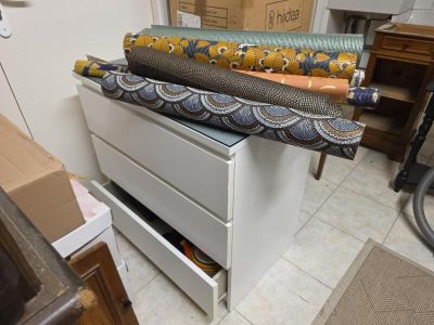 Plusieurs rouleaux de tissu sont posés sur un tiroir dans une pièce.