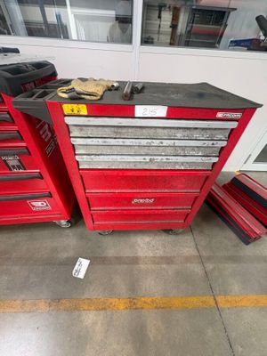 un groupe de caisses à outils rouges posées sur le sol d'un garage