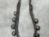 an image of a leather necklace with bells on a concrete floor