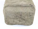 a tan bag sitting on a white surface with dirt all over it