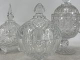 three clear glass jars with lids sitting on a table