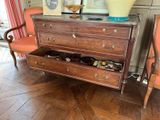 une commode dans un salon, sur laquelle est posé un vase