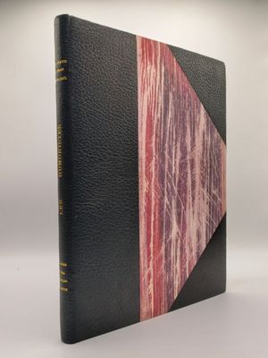 un vieux livre avec une couverture rose et noire posée sur une surface blanche