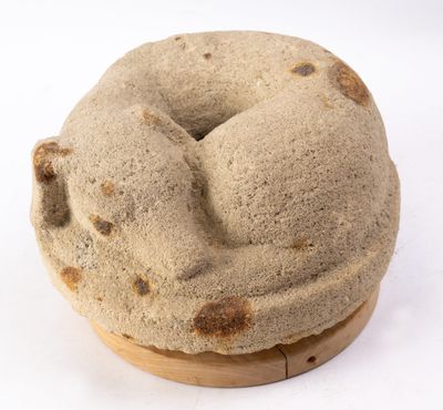 un beignet posé sur une assiette en bois, sur une surface blanche