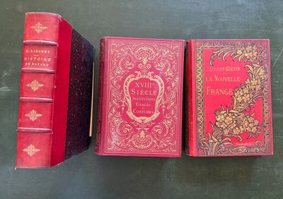 trois livres rouges posés les uns à côté des autres sur une table