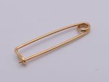 a gold safety pin on a white background