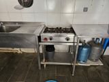 a kitchen with a stove, sink, and a pot on the floor