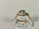 a gold ring with green and white stones on it