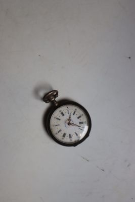 une petite montre de poche posée sur une table blanche