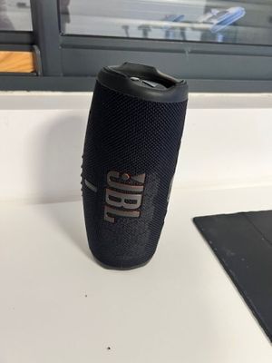the jbl flip portable speaker sits on a table next to a laptop