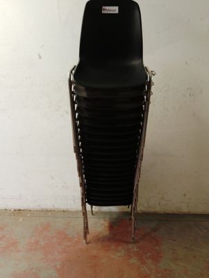 une pile de chaises noires dans une pièce aux murs blancs