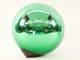 a shiny green ball with a wooden base on a white surface