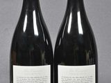two bottles of red wine sitting next to each other on a table