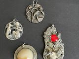 three silver pendants with a red bead on a black surface