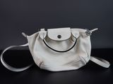 sac à main blanc avec une poignée noire sur un fond noir