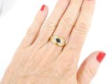 woman ' s hand with red manicured nails and a gold ring with a black stone
