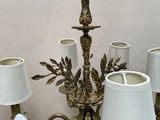 a chandelier with five lamps and a bird on top of it