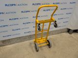 a yellow hand truck that is sitting in front of a wall