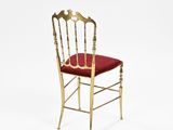 a gold chair with a red cushion on a white background