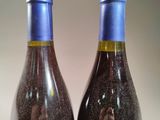 two bottles of wine are sitting on a table with sand in them