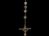 a close up of a cross hanging from a chain on a black background