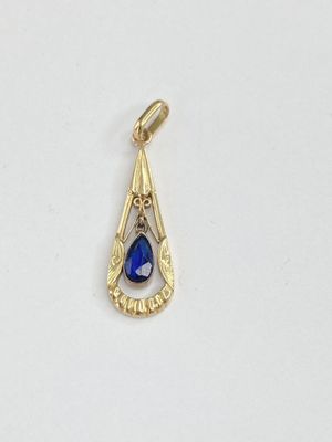 un gros plan d'un pendentif bleu en forme de larme posé sur une surface blanche