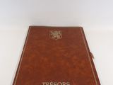 un livre en cuir marron, avec une inscription blanche, posé sur une surface blanche