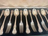 a lot of silver spoons and forks in a box