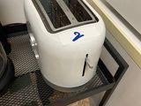 a white toaster sitting on top of a metal shelf