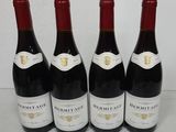 four bottles of red wine are lined up on a table