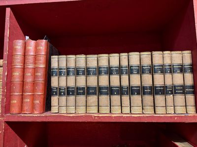 de nombreux livres anciens sur une étagère rouge dans la pièce