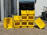 Plusieurs bacs jaunes sont empilés devant un immeuble