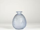 un vase en verre bleu posé sur une surface blanche