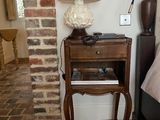 une petite table sur laquelle est posée une lampe, à côté d'un lit