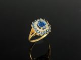 une bague en or sertie d'un saphir bleu et de diamants, sur un fond noir